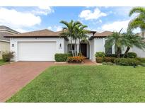Charming single-story home with lush landscaping, brick driveway, and attached two-car garage at 1034 Buttercup Gln, Bradenton, FL 34212