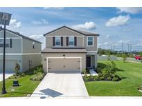 Charming two-story home featuring a well-manicured lawn and a convenient two-car garage at 10464 Ladybug Cv, Parrish, FL 34219
