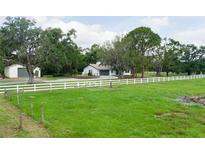 Sprawling home exterior featuring a white fence, large trees, and a detached garage at 5403 Red Rooster Rd, Parrish, FL 34219