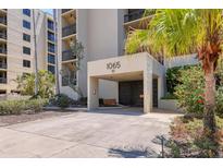 Welcoming condo entrance with covered parking and tropical landscaping, providing a serene arrival experience at 1065 Gulf Of Mexico Dr # 103, Longboat Key, FL 34228
