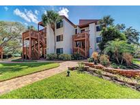 Inviting condo complex with tropical landscaping, wooden staircases, and a brick walkway to the charming building entrance at 1200 Cove Ii Pl # 832, Sarasota, FL 34242