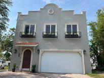 Two-story gray home with a garage, arched wood door, paver driveway and black flower boxes on the second story at 2221 Bahia Vista St, Sarasota, FL 34239