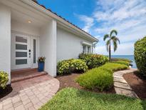 Beautiful waterfront home featuring a manicured lawn, colorful landscaping, and a charming walkway to the front door at 2282 Harbour Court Dr, Longboat Key, FL 34228