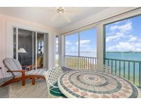 Inviting sunroom features a decorative tile table and comfortable lounge chair with beautiful water views at 242 Hidden Bay Dr # 603, Osprey, FL 34229