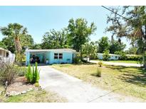 Charming single-story home with a light blue exterior, carport, mature trees and landscaping at 305 Palmetto W Rd, Nokomis, FL 34275