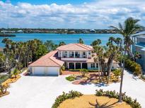 Coastal home boasting a three-car garage, lush landscaping, and a stunning waterfront view at 3300 Casey Key Rd, Nokomis, FL 34275
