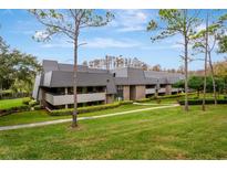 Low angle exterior of gray two-story condominium building on grassy hill with trees at 36750 Us 19 N # 03102, Palm Harbor, FL 34684