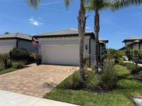 Charming single Gathering home with paved driveway and lush tropical landscaping and beautiful blue sky at 12291 Myrtle Bay Ct, Sarasota, FL 34238