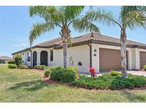 Charming home featuring a tile roof, two-car garage, and mature landscaping with palm trees at 12640 Felice Dr, Venice, FL 34293