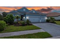 Charming one-story home featuring a manicured lawn, beautiful landscaping, and an attached two-car garage at 13319 Deep Blue Pl, Bradenton, FL 34211