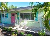 Charming home with a colorful exterior, inviting porch, and beautiful landscaping at 205 Elm Ave, Anna Maria, FL 34216
