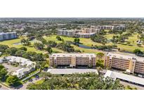 Scenic aerial view of the golf course community featuring lush greenery, ponds, and multi-story condo buildings at 3750 Pinebrook Cir # 104, Bradenton, FL 34209