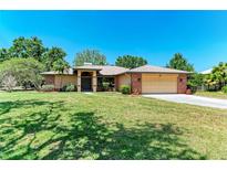 Charming single-story home featuring a well-manicured lawn, mature trees, and an attached two-car garage at 410 136Th E Ct, Bradenton, FL 34212