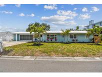 Charming one-story home with a blue exterior, well-manicured lawn, and lovely tropical landscaping and palm trees at 4309 Pinfish Ln, Palmetto, FL 34221