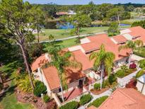 Beautiful home with red tile roof, palm trees and lush landscaping overlooking pond and golf course at 5336 Huntingwood Ct # 24, Sarasota, FL 34235