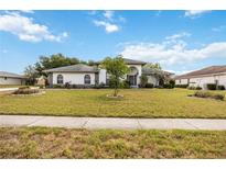 Charming one-story home with a well-manicured lawn and lush landscaping under a sunny blue sky at 6405 99Th E St, Bradenton, FL 34202