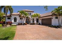 Elegant single-story home with a tile roof, brick driveway, and lush tropical landscaping at 11447 Savannah Lakes Dr, Parrish, FL 34219