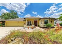 Charming yellow home featuring a red front door, well-manicured lawn, and a two-car garage at 127 Mill E Run, Bradenton, FL 34212