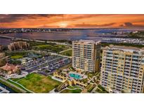 Stunning sunset view of luxury high-rise condos with a pool, lush landscaping, and ample parking near the bay and city at 130 Riviera Dunes Way # 502, Palmetto, FL 34221
