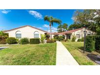 Charming single-story home featuring a well-manicured lawn, vibrant landscaping, and a welcoming walkway to the entrance at 2259 Pueblo Ln # V38, Sarasota, FL 34231