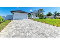 Beautiful home featuring a long, patterned driveway and a well-manicured lawn under a clear blue sky at 380 Holly Rd, Venice, FL 34293