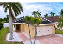 Charming home with a brick driveway, palm trees, and a two-car garage, offering curb appeal at 4826 San Ortebello Dr, Bradenton, FL 34208