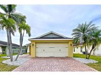 Charming home featuring a two-car garage, brick driveway, and lovely landscaping with decorative stones and palm trees at 4826 San Ortebello Dr, Bradenton, FL 34208