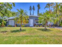 Charming home with lush green lawn, swaying palms, and a freshly painted exterior on a sunny day at 6013 Murdock Ave, Sarasota, FL 34231