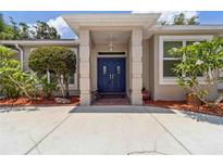 Inviting front entrance with a double blue door, pillars, and mature landscaping adds to the curb appeal of this lovely home at 6110 Misty Oaks St, Sarasota, FL 34243