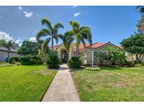 Beautiful home with a red tile roof, lush landscaping, and a brick walkway leading to the front door at 8005 Royal Birkdale Cir, Lakewood Ranch, FL 34202