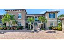 Beautiful condo building featuring lush landscaping, a paver driveway, and elegant architectural details under a bright blue sky at 12720 Sorrento Way # 103, Bradenton, FL 34211