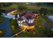 Stunning aerial view of an estate home with a barn, screened pool, pond, and lush landscaping all around at 19006 69Th E Ave, Bradenton, FL 34211