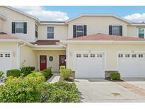 Inviting two-story townhouse with attached garage, manicured landscaping, and brick-lined driveway at 2353 Rosewood Ln, North Port, FL 34289