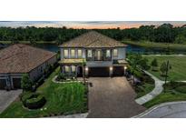 Elegant two-story home with a tile roof, paver driveway and three-car garage, located on a waterfront lot at 2806 Starwood Ct, Lakewood Ranch, FL 34211