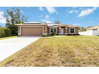 Charming single-story home featuring a two-car garage, neutral stucco, manicured lawn, and bright solar panels at 3453 Dryden St, North Port, FL 34288