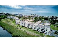 Beautiful aerial view of a waterfront condo building with lush landscaping near the beach and water at 4800 Gulf Of Mexico Dr # 204, Longboat Key, FL 34228