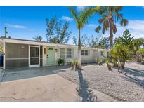 Charming single-story home with a screened-in porch, a quaint bench, and lush tropical landscaping at 578-580 Companion Way, Longboat Key, FL 34228