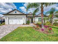 Charming home featuring a well-manicured lawn, landscaped flower beds, and a brick driveway leading to a two-car garage at 749 Tailwind Pl, Sarasota, FL 34240