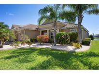 Beautifully landscaped home with lush green lawn, colorful bushes, and mature palm trees at 8297 Barton Farms Blvd, Sarasota, FL 34240