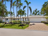 Charming single-story home featuring a brick driveway and beautiful landscaping with mature palm trees at 1014 Contento St, Sarasota, FL 34242