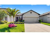 Charming single-Gathering home with a well-manicured lawn, complemented by a vibrant palm tree and flower bed at 4722 Lindever Ln, Palmetto, FL 34221
