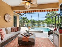 Relaxing screened lanai with comfortable seating, outdoor kitchen, and pool overlooking a serene lake view at 521 Habitat Blvd, Osprey, FL 34229
