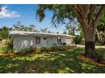 Charming single-story home with a well-manicured lawn and a cozy front porch seating area at 709 84Th Nw St, Bradenton, FL 34209