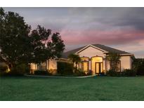 Inviting single-story home with a lush lawn and manicured landscaping, beautifully lit at dusk at 8121 Snowy Egret Pl, Bradenton, FL 34202