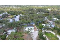 Aerial view of home surrounded by lush landscape; view of private dock, canal access, and serene backyard at 1130 Mill Creek Rd, Bradenton, FL 34212