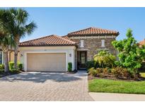 Beautiful single-story home featuring a tile roof, stone accents, and a two-car garage, complemented by lush landscaping at 2525 Vaccaro Dr, Sarasota, FL 34231
