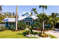 Charming blue home boasts lush landscaping and a well-manicured lawn, creating a welcoming curb appeal at 403 75Th St, Holmes Beach, FL 34217