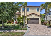 Two-story home boasts lush landscaping, a brick driveway, and a neutral-toned exterior with a two-car garage at 5503 Title Row Dr, Bradenton, FL 34210