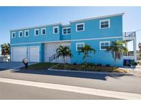 Stunning two-story home with a vibrant blue exterior, two-car garage, and neatly manicured landscaping at 654 Jungle Queen Way, Longboat Key, FL 34228