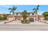 Inviting exterior of a townhome with paver driveway, mature palms, and a two-car garage at 6914 Grand Estuary Trl # 101, Bradenton, FL 34212